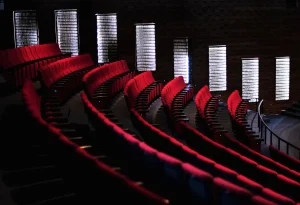 Aménagement des sièges d’auditorium avec des rangées courbes de fauteuils rouges face à un mur lumineux