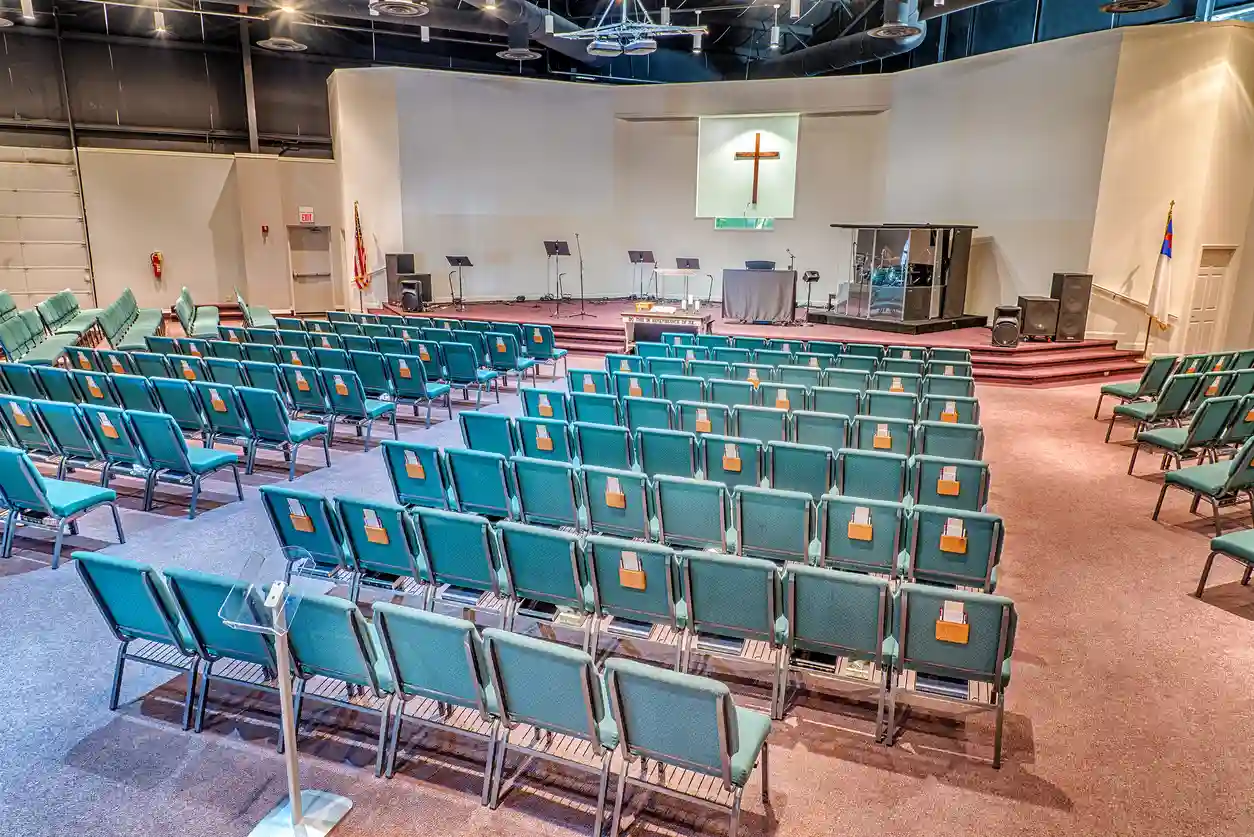 Teal upholstered church chairs linked in curved rows facing the sanctuary stage